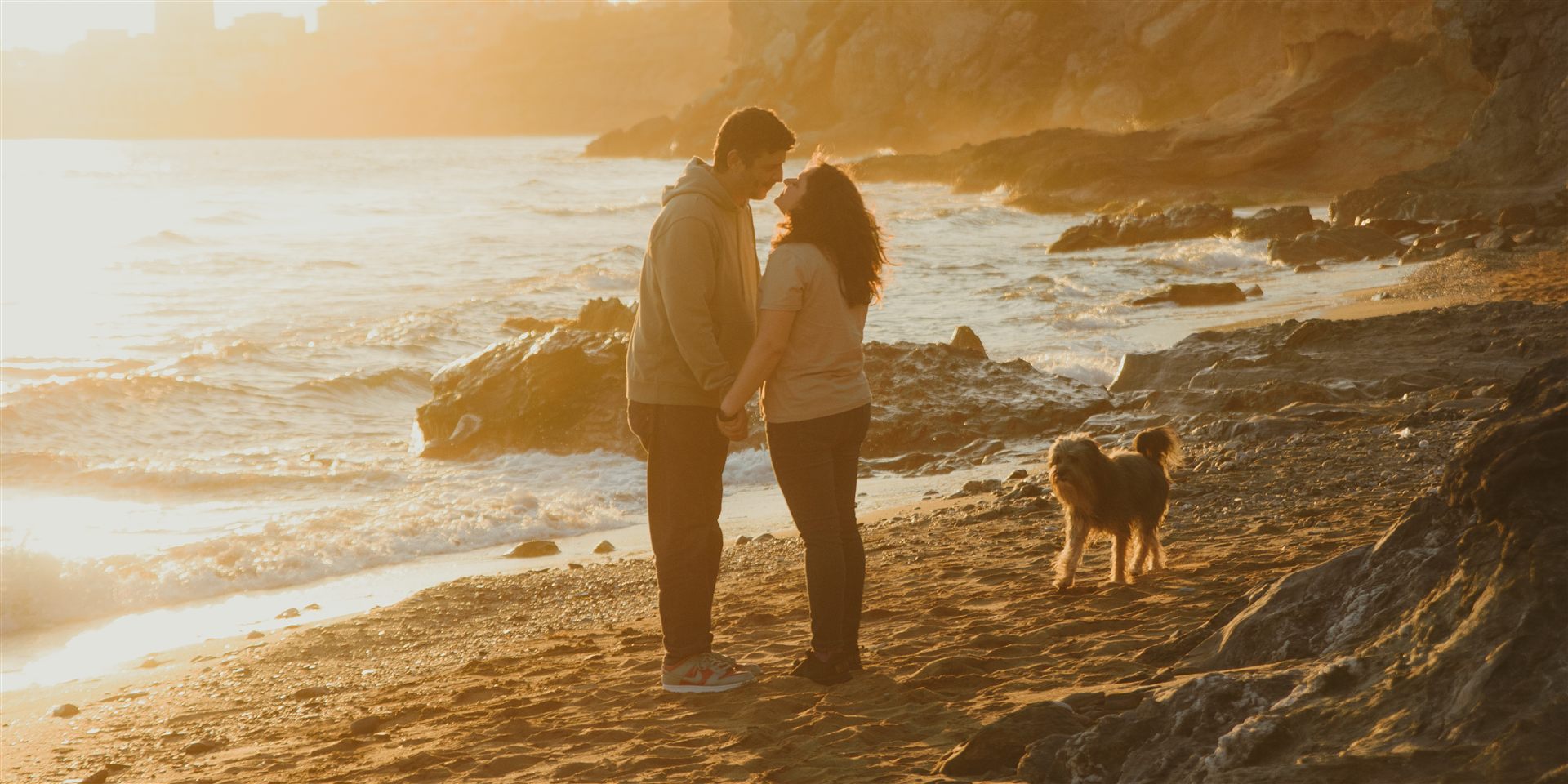 Pareja frente a frente con su perro al atardecer en la playa de Águilas — Luarna Studio